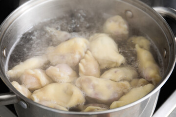 Preparing Ukrainian dumplings (varenyky) in pot, closeup