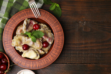 Traditional Ukrainian dumplings (varenyky) with cherries served on wooden table, flat lay. Space for text