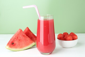 Tasty watermelon drink in glass and fresh fruit on white wooden table