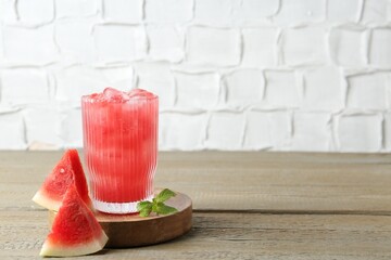 Tasty watermelon drink in glass, mint and fresh fruit on wooden table, space for text