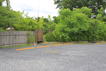 Empty parking spaces in public park with bumps barrier against bamboo wooden fence.