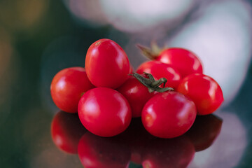 tomatoes on the vine, the delicious ripe red cherry tomatoes on the reflected plane during the day, exquisite datterini.A vibrant close-up, where the tomatoes are ripened in the sun, the morning light