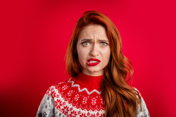 Portrait photo of young lady guilty biting lips wearing ugly sweater celebrating christmas holiday isolated on red color background