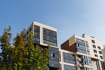 residential apartment building among green trees against blue sky