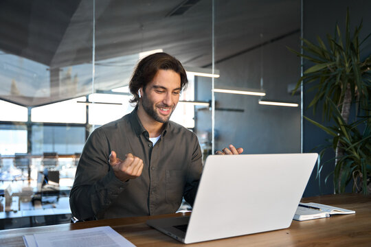 Happy business man in earbuds using laptop communicating on video call. Male hr manager professional executive in office looking at computer having conference online hybrid work meeting job interview.