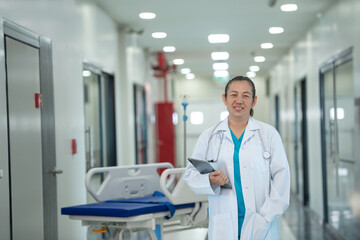 Naklejka premium A female doctor stands smiling, holding a tablet in her hand, preparing to work at the hospital