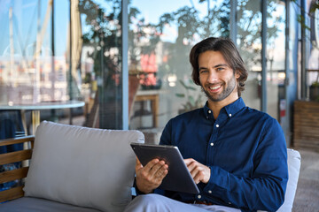 Portrait of happy handsome elegant young business man entrepreneur holding pad computer at work....