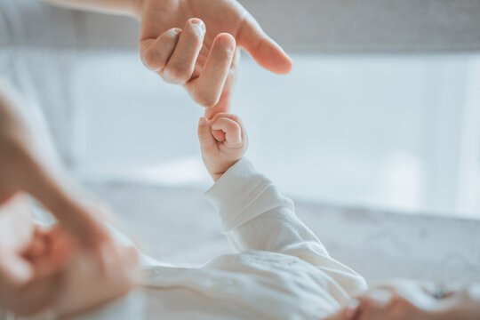 Little hand of child baby holding hand of mother, A newborn holds on to mom's, dad's finger, Love and relationship family with infant, Care and support, Dreaming and protection