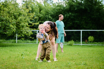 Fototapeta premium Happy family playing badminton on green grass in summer park