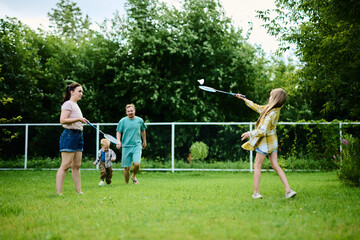 Obraz premium Happy family playing badminton on green grass in summer park
