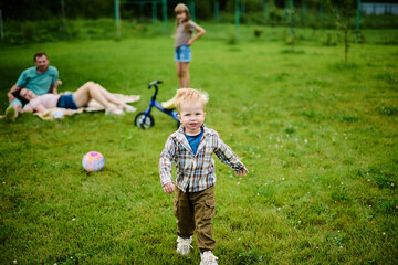 Happy Caucasian family on picnic having fun, eating and playing games on green grass