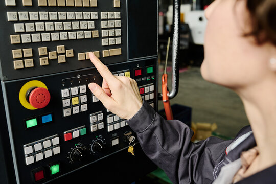 Person manually operating control panel of industrial machinery in a factory environment 