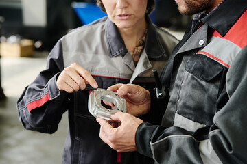Caucasian mechanics examining car component with focus on details and quality in automotive repair shop environment
