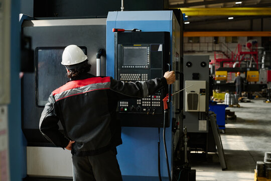 Worker in protective gear operating industrial machinery at manufacturing facility 