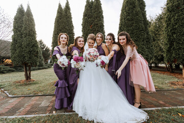 A group of women posing for a picture in front of a tree. One of the women is wearing a white dress