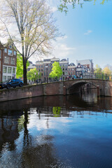 Facades of old historic Houses, bridges and trees over canal water, Amsterdam, Netherlands
