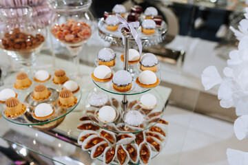 A table with a variety of desserts, including cakes and pastries, arranged on a glass display