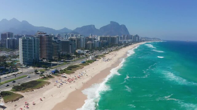 Aerial view of Barra da Tijuca Beach in Rio de Janeiro, Brazil, with turquoise waters and coastal buildings.