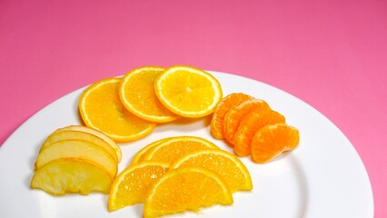 summer fresh fruits slice decorated on white ceramic plate with pink background 