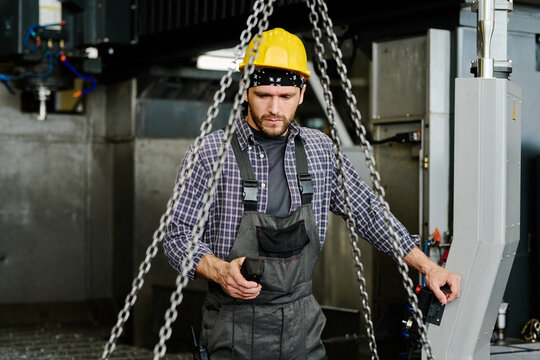 Worker manipulating chains and industrial machinery in manufacturing environment 