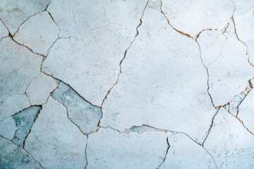 Fototapeta premium Close-up of a weathered wall with visible cracks and peeling paint, showcasing textures and details perfect for backgrounds, construction, or abstract designs.