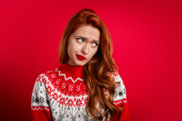 Photo portrait of alone cute guilty young lady wearing festive xmas sweater feel sad looking empty space isolated on red color background