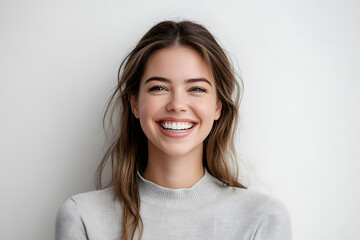 Fototapeta premium Headshot of good-looking lucky woman with tied hair pure skin and broad smile being happy to watch at camera. Sincere female with beautiful appearance wearing casual clothes isolated over white wall