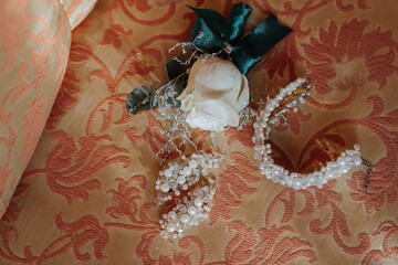 A white flower is on top of a piece of cloth. The cloth is orange and has a pattern
