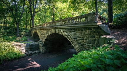 A historic stone bridge with deep shadows under its arches, framed by lush greenery on either side, blending nature with architecture.