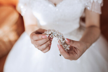 A woman is holding a piece of jewelry in her hand. The woman is wearing a white dress, and the necklace complements her outfit. Concept of elegance and sophistication