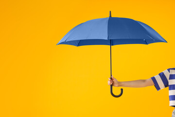 Woman with blue umbrella on yellow background, closeup