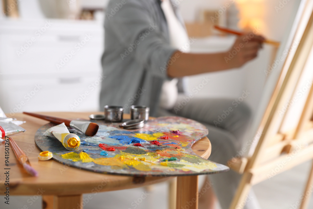 Canvas Prints Woman painting on easel indoors, focus on palette and brushes