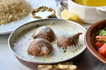  A traditional Lebanese dish of Kibbeh bil Laban, featuring tender kibbeh balls made from ground...