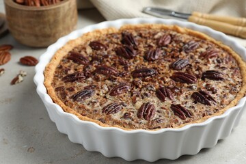 Delicious pecan pie in baking dish on gray table, closeup