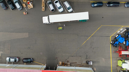 Drone photography of a forklift unloading cargo from a truck during summer day
