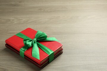 Books with ribbon as gift on wooden table, space for text