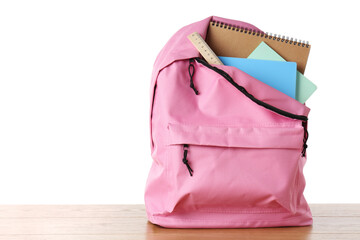 Backpack with notebooks and ruler on wooden table against white background, space for text