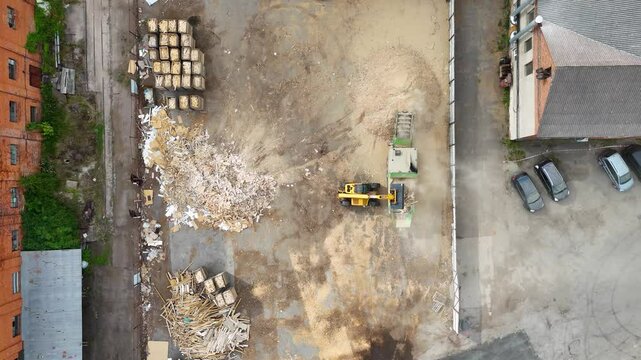 Drone footage of a telehandler moving wood to a grinder during summer day