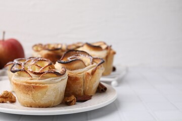 Puff pastry. Freshly baked apple roses and walnuts on white tiled table, closeup. Space for text