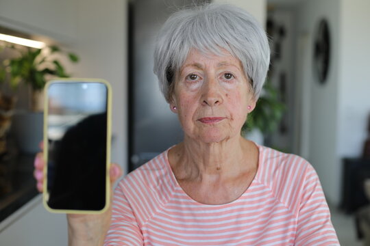 Worried looking senior  woman showing her cellphone screen