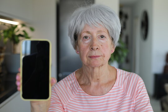Worried looking senior  woman showing her cellphone screen
