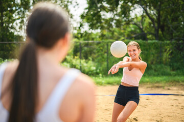 two teen girls play beach volleyball in summer