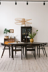 Large oval table with vase of flowers in the center and lamp hanging above it, surrounded by black chairs