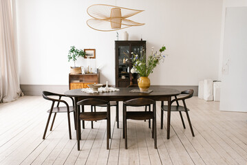 Large oval table with wooden chairs and vase of flowers in the center. Dining room is clean and...