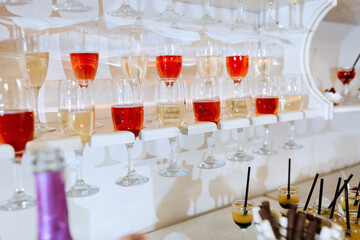 A row of wine glasses are lined up on a shelf, with some of them containing red wine