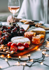 Wooden board with different kinds of cheese and glass of rose wine. Dinner or aperitivo party concept.