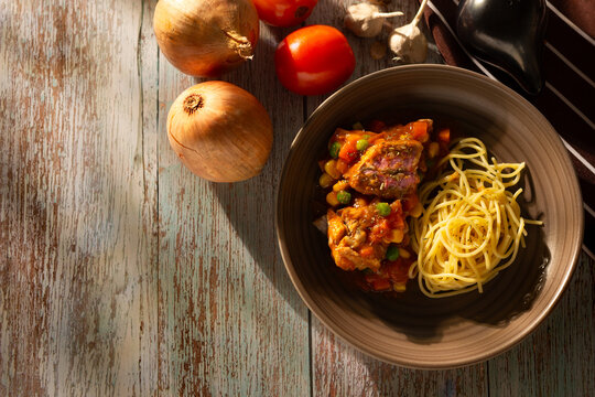 A plate of spaghetti with pork pasta in tomato sauce and pasta with pork and vegetables.