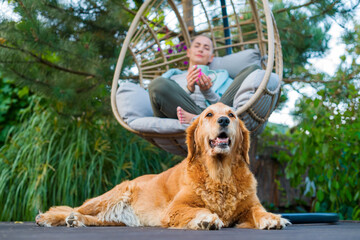 Young female cancer patient relaxing in hanging chair on the patio with her emotional support...
