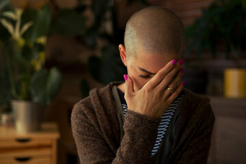Young female cancer patient with head in hands indoors portrait. Mental health, emotional support,...