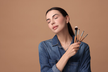 Obraz premium Beautiful makeup. Attractive woman with brushes on beige background, space for text